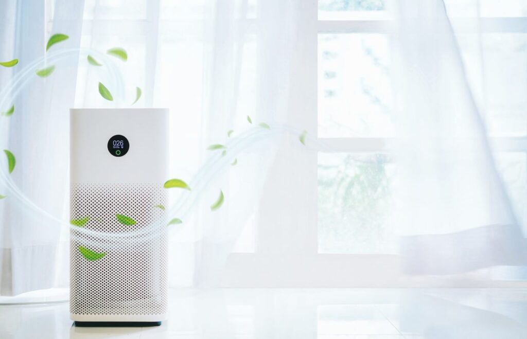 Picture of an air purifier in a white background with airy curtains.