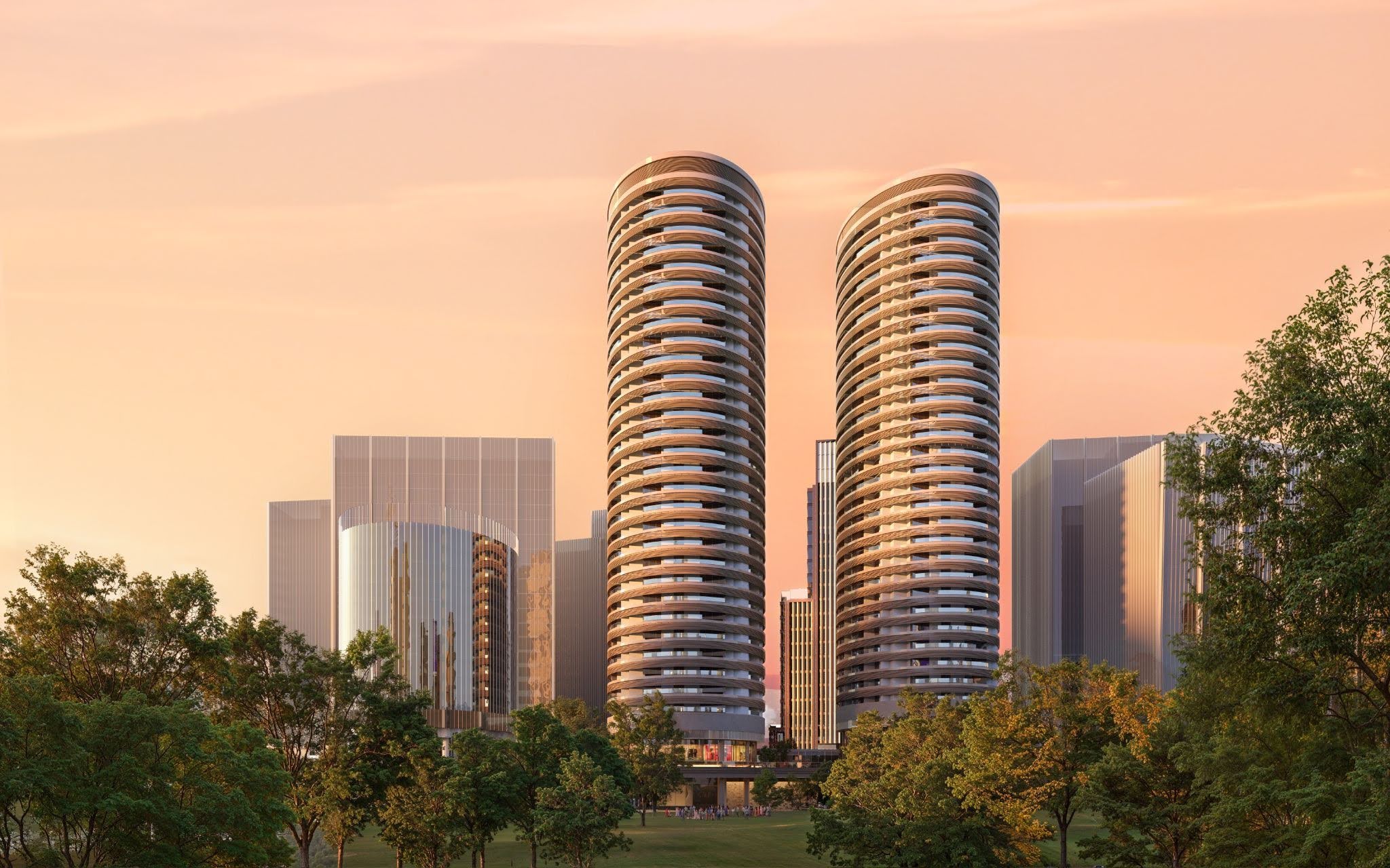 Modern twin curved residential skyscrapers at sunset, surrounded by greenery and contemporary city buildings, with warm golden light reflecting on glass facades. 