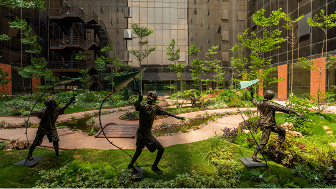 Max Square commercial courtyard featuring bronze statues and green landscaping